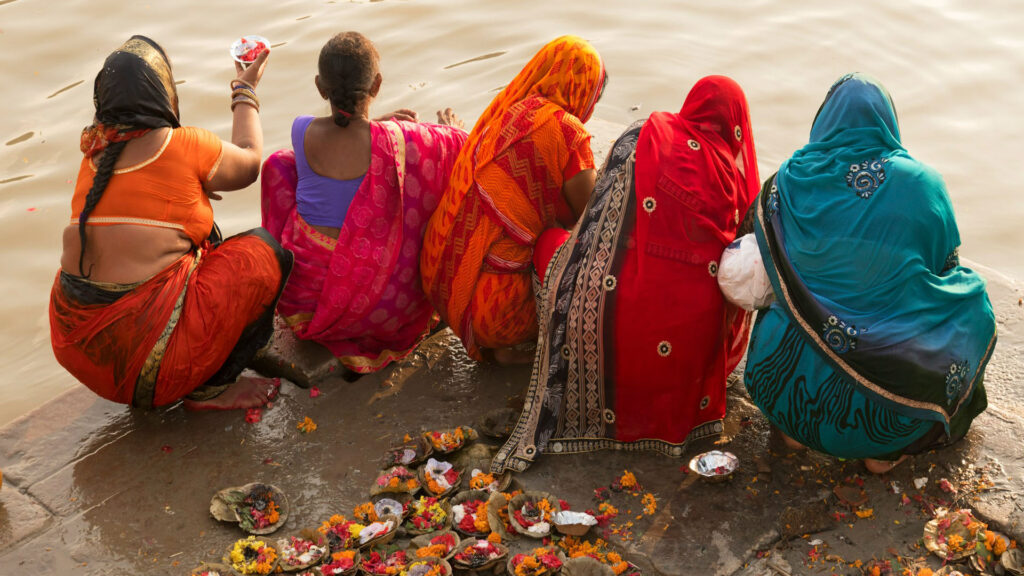 Hindu women in bright saris praying by the Ganga
